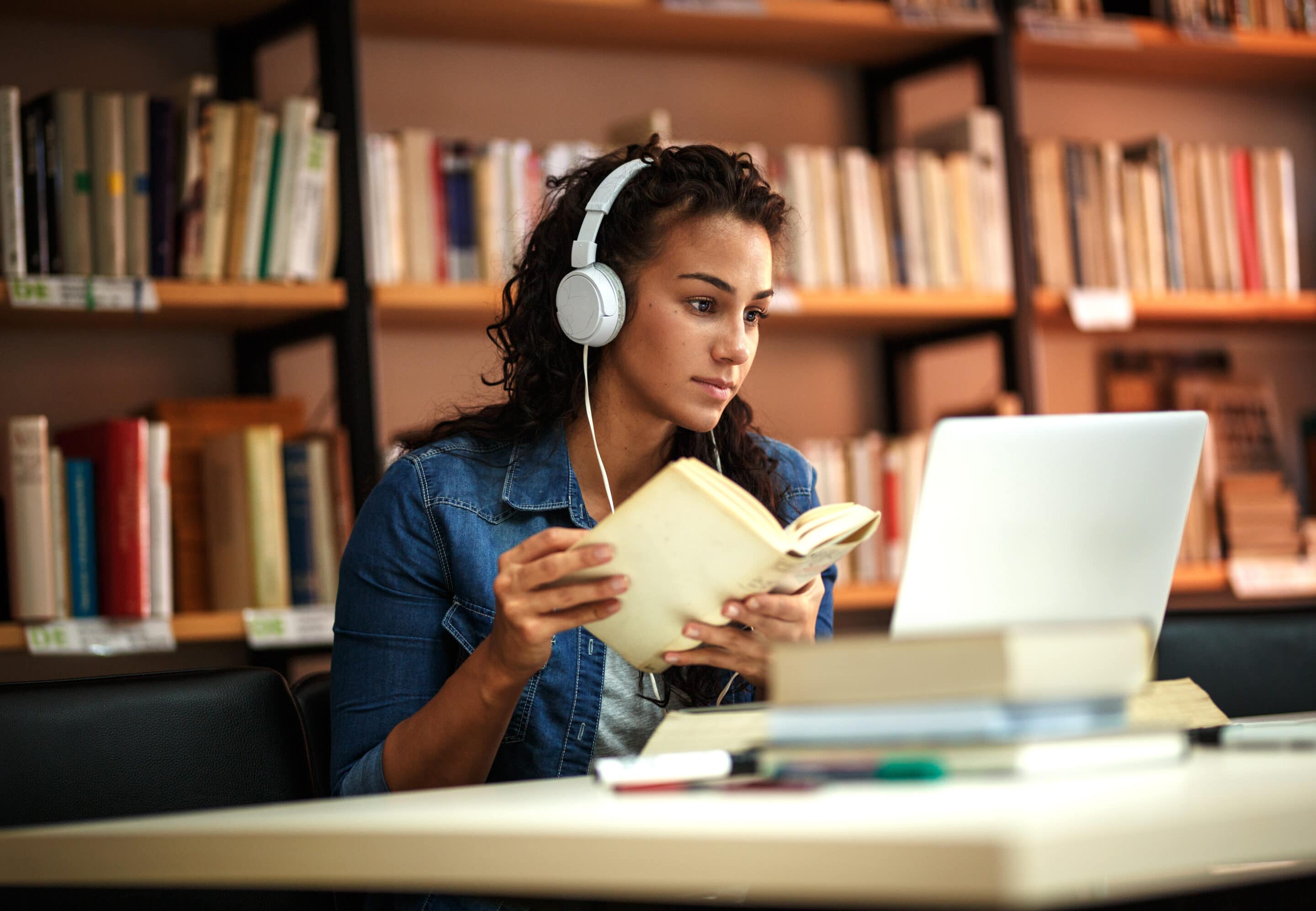 étudiante-avec-livre-dans-la-main-et-ordinateur